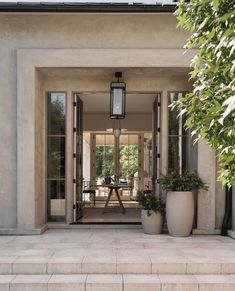 an entrance to a house with two large planters on the steps and a lamp hanging from the ceiling