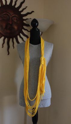 a mannequin with a yellow necklace on it's neck next to a sun sculpture