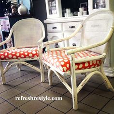 two white wicker chairs with red and white polka dot cushions sit in front of a china cabinet