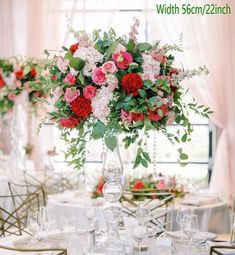 a vase filled with lots of flowers on top of a table covered in white linens