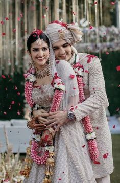 two people standing next to each other in front of confetti falling from the sky