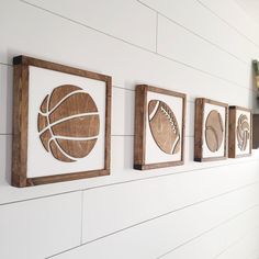 three wooden wall hangings with sports balls on them, mounted to the side of a white wall