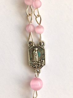 Handmade with small 4mm and 6mm pink cats eye beads and silver metal wire. I love the cats eye beads because of the ribbon of light that appears and follows the sun. Small Our Lady of Fatima medal and small crucifix. Comes with a gift pouch Pink Spiritual Rosary Bracelet With 8mm Beads, Pink 8mm Bead Spiritual Rosary Bracelet, Pink 8mm Beads Rosary Bracelet, Handmade Pink Rosary For First Communion, Pink Rosary With 8mm Round Beads, Pink Rosary With 8mm Beads For Gift, Pink Rosary With 8mm Beads As Gift, Adjustable Pink Rosary Bracelet For First Communion, Pink Rosary With Miraculous Medal As A Gift