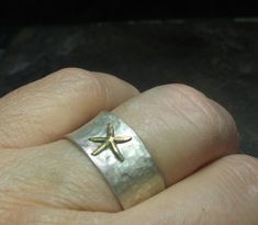 "Starfish ring - express your inner beachcomber with this cute little sterling silver starfish ring! A golden brass starfish rests on a background of brushed sterling silver to bring a hint of the beach to your day. A perfect little ring comfortable to wear and easy to mix and match with many styles both dressy and casual. The ring is 10mm wide (3/8\"), and has been hammered with a texture to remind of the dappled surface of a tidal pool. The finish is a brushed satin finish that allows the star Silver Starfish Jewelry For Beach, Unique Starfish Jewelry As A Gift, Ocean-inspired Sterling Silver Starfish Jewelry, Beachy Starfish Jewelry Gift, Silver Starfish Charm Jewelry For Summer, Silver Jewelry With Starfish Charm For Summer, Handmade Starfish Jewelry In Beachy Style, Handmade Starfish Beachy Jewelry, Handmade Beachy Starfish Jewelry