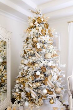 a white christmas tree with gold and silver ornaments