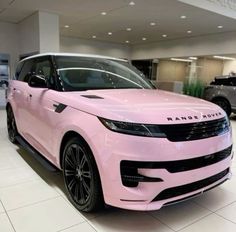 a pink range rover parked in a showroom