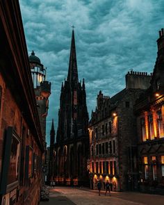 people are walking down the street in front of old buildings at night with lights on