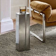 a silver flask sitting on top of a rug next to a chair and ottoman