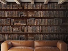 a leather couch sitting in front of a bookshelf filled with lots of books