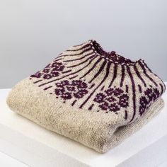 a white and purple sweater sitting on top of a box