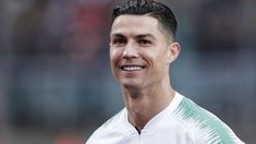 a close up of a soccer player wearing a white shirt and black hair smiling at the camera