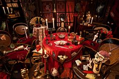 a table covered in red cloths with candles and skulls on it, surrounded by other items