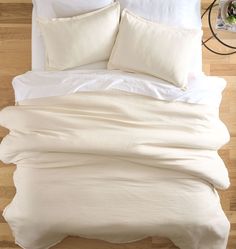 an overhead view of a bed with white linens and pillows on top of it