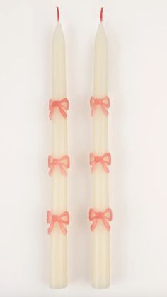 two white candles with pink bows on them