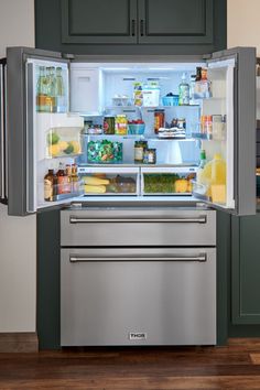 THOR Kitchen refrigerator in stainless steel built into green cabinet kitchen doors. Refrigerator has french doors that are both open, displaying a fridge full of groceries. The refrigerator drawer and freezer drawer are closed. December Crafts, Cool Look, All This Time, My Clothes