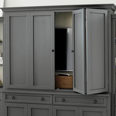 a gray armoire with two doors and baskets in it's bottom drawer area