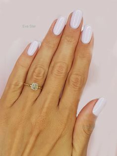 a woman's hand with white manicures and a gold ring