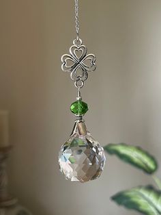 a glass ornament hanging from a chain with a green bead on it