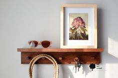 a wooden shelf with two keys, sunglasses and a rope hanging on the wall next to it