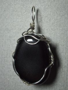 Apache Tear Pendant Wire Wrapped in .925 Sterling Silver Round Wire This beautiful stone, originated from a volcanic eruption, is of a relatively consistent translucent light smoky grey-brown color, yet still appears black in reflected light, against most backgrounds. It wears well with almost any color of clothing, as it compliments either grey or brown based color tones. An exception might be black, since this stone will appear black on black. Consistent color and near flawless appearance make Elegant Obsidian Jewelry For Healing, Handmade Black Jewelry For Memorial, Silver Obsidian Jewelry For Healing, Silver Onyx Jewelry With Large Stone, Classic Silver Agate Jewelry, Apache Tears, Volcanic Eruption, Reflected Light, Stone Wrapping