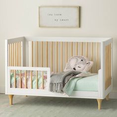 a baby crib with a blanket on top of it next to a wall hanging