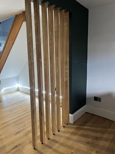 an empty room with wood floors and wooden slats on the wall, next to a stair case