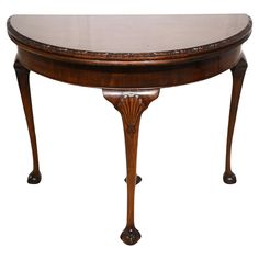 an oval wooden table with ornate carvings on the top and bottom, against a white background