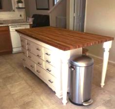 a kitchen island with drawers and a trash can