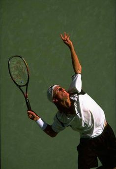 a man holding a tennis racquet on top of a tennis court with his hand in the air