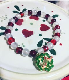 With white glass beads that shimmer like snowflakes and assorted red glass beads that glimmer like Holly berries, it's no wonder this 7 ½ inch double threaded stretch and Holly Charm bracelet is a sight to behold. Choking Hazard!  Keep away from small children and pets. Christmas Jewelry With Faceted Round Beads, White Beaded Bracelets For Holidays, Christmas Jewelry With Round Faceted Beads, White Christmas Jewelry With Colorful Beads, Holiday White Beaded Jewelry, Festive White Beaded Bracelets With Colorful Beads, Festive Beaded Stretch Bracelet, White Bracelets With Colorful Beads For Christmas, Christmas Jewelry With Round Spacer Beads