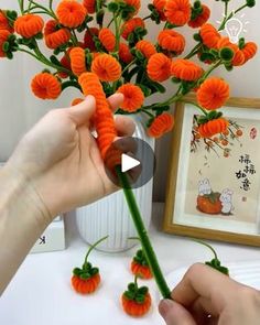 someone is arranging orange flowers on a white table with a framed picture in the background