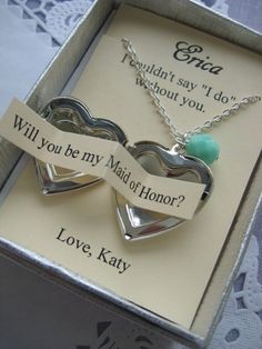 two silver heart shaped pendants with ribbon saying will you be my maid of honor?