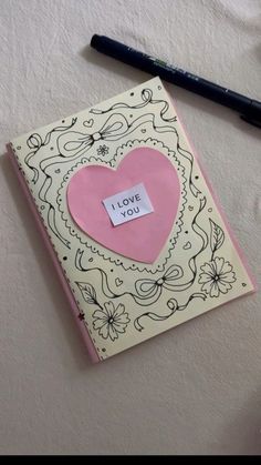 a notepad with a pink heart and i love you written on it next to a pen