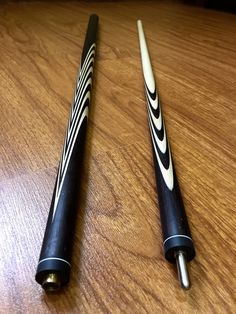 two black and white baseball bats sitting on top of a wooden table next to each other