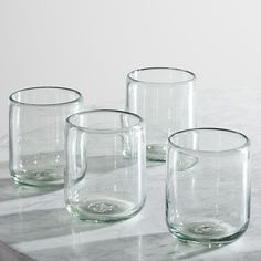 three clear glass cups sitting on top of a marble table