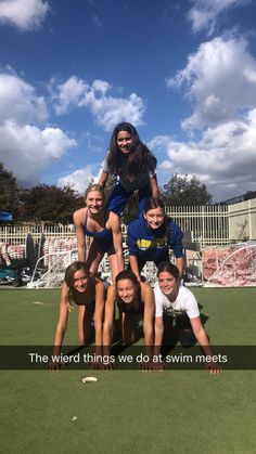 a group of young people standing on top of each other in front of a green field