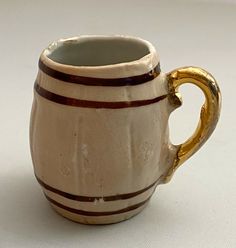 a white and brown striped mug with gold handles