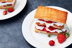 two plates with sandwiches and strawberries on them