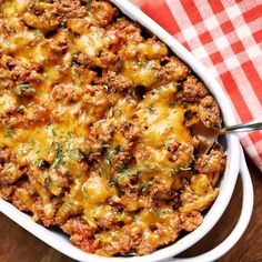 a casserole dish filled with meat and cheese on a red checkered napkin