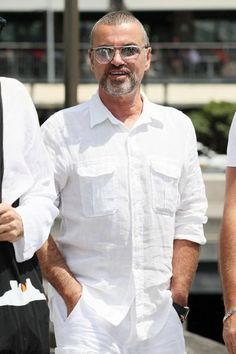 a man in white shirt and shorts standing next to two men wearing black sunglasses on the street