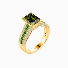 a yellow gold ring with an emerald and diamond set in the center, on a white background