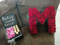 the letter m is made out of flowers and chocolates in front of a box