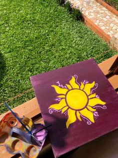 an easel and some paint sitting on a wooden table in front of a grassy area