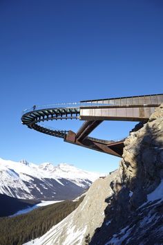 a man riding a snowboard down the side of a mountain next to a bridge