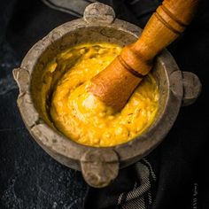 a wooden spoon in a bowl filled with yellow food