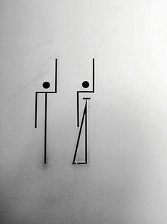 two metal poles with faces on them in front of a white wall and black floor