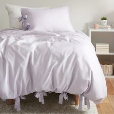 a bed with white sheets and pillows on top of it in a room next to a book shelf