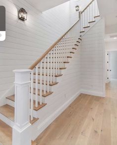 a white staircase with wooden handrails and wood flooring in an empty room