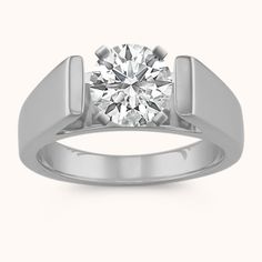 a white gold ring with a round diamond in the center and an arrow design on the band