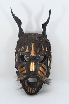 an elaborate mask with horns and spikes on it's face is seen against a white background